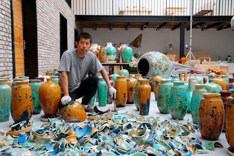 picture of artist surrounded by ceramic vessels